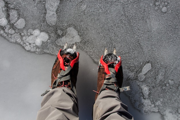 アイゼンを氷の上に置いた2つのハイキングブーツ。マウンテンスポーツアクセサリーのコンセプト