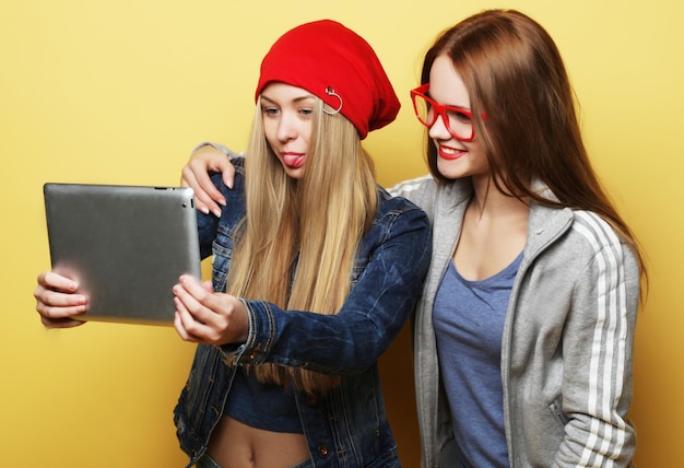 Two hipster girls friends taking selfie with digital tablet