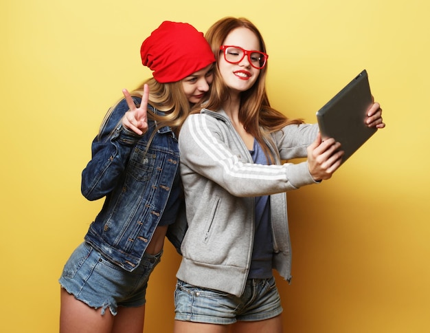 Две хипстерские подруги, делающие селфи с цифровым планшетом