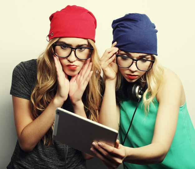 Two hipster girls friends use digital tablet