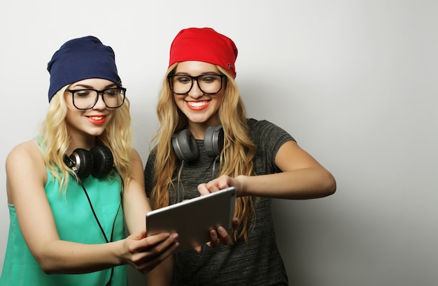 Two hipster girls friends use digital tablet