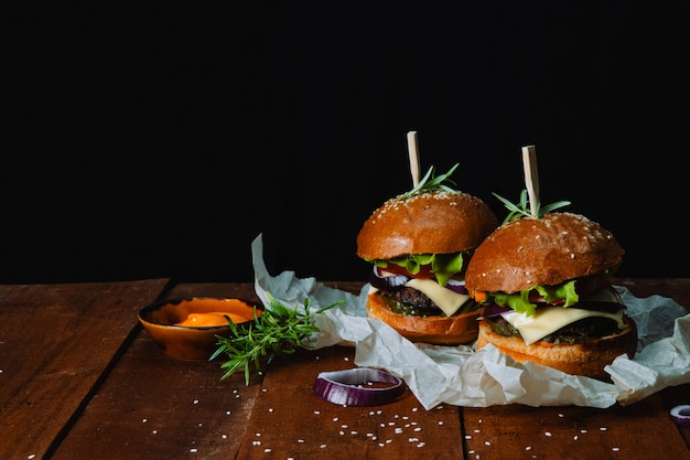 Two homemade hamburgers with sauce on a wooden table 