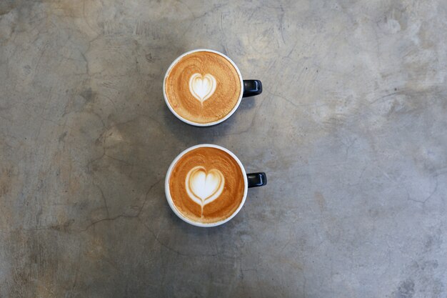 Two hot cups of cappucino on concrete background Valentines day concept