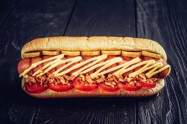 Two hot dogs with ketchup closeup , yellow mustard and onion on gray wooden surface.