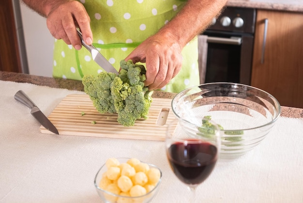 年配の男性の 2 つの人間の手がブロッコリーの野菜を切ってきれいにする 健康的な食事