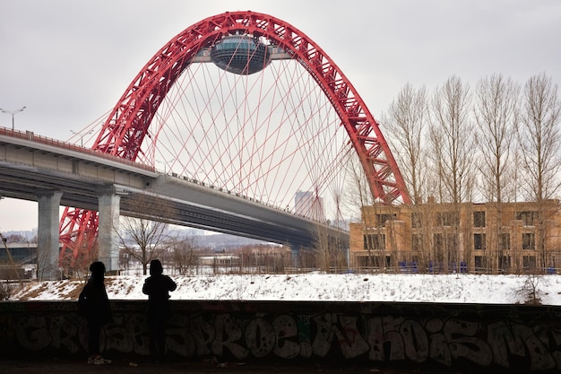 Two human silhouettes on the background of the road bridge with a red arch