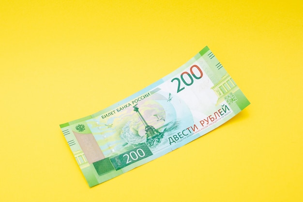 Two hundred ruble bill on a yellow paper background.