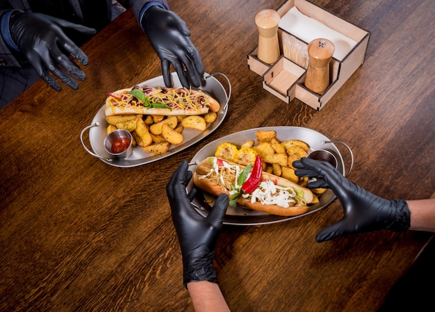 Two hungry young men eating a hot dogs in cafe. Restaurant