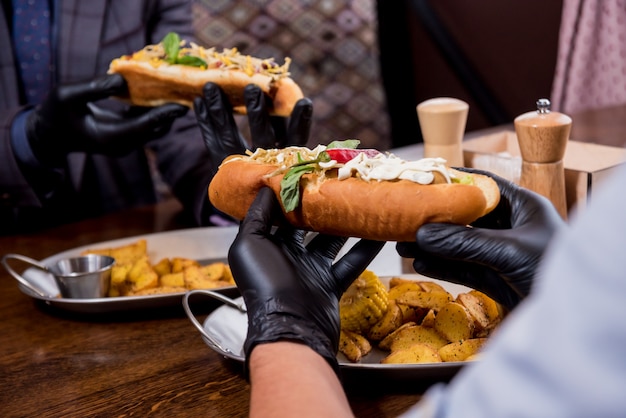 Photo two hungry young men eating a hot dogs in cafe. restaurant