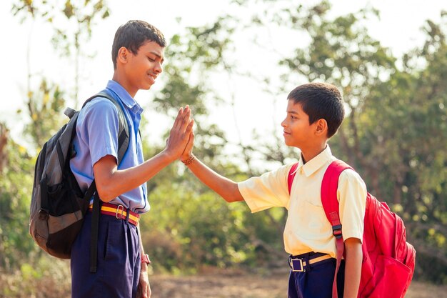 学校で会い、屋外のゴアでハイタッチをする2人のインド人兄弟