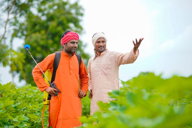 Due agricoltori indiani che lavorano e discutono al campo di cotone verde.