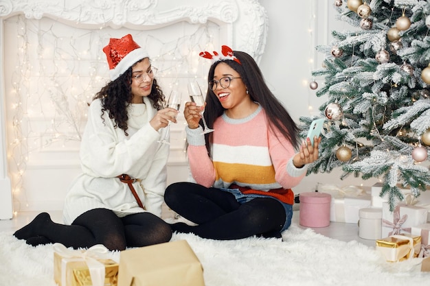 Two indian girl in eyeglasses holding a glass of champagne and making a selfie