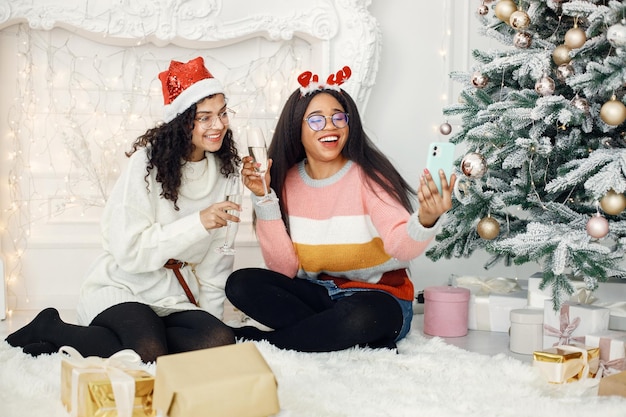 Two indian girl in eyeglasses holding a glass of champagne and making a selfie