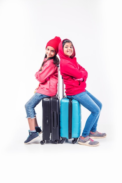 Two Indian girls with suitcase while wearing warm cloths, ready for winter holidays
