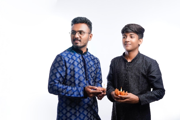 Two Indian men wears ethnic or traditional cloths Male fashion models with sherwani or Kurta Pyjama standing and holding Diwali lamp over white background selective focus