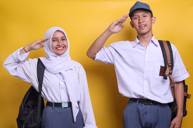 Two Indonesian high school students in white and grey uniform doing salute in an act of honor and pa