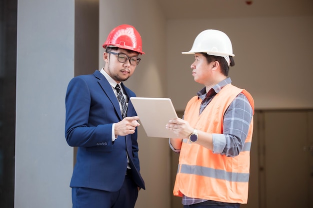 Two Industry Engineers Stand in modern building construction Use Digital Tablet