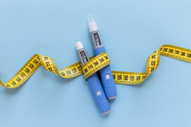 Photo two injectors dosing pens for subcutaneous injection of antidiabetic medication or antiobesity medication hovering over a blue background yellow measuring tape around the injectors