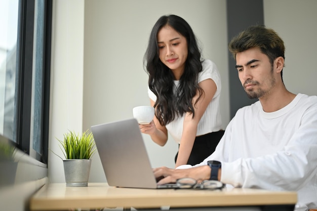 Two of intelligent Asian millennial male and female business worker working together