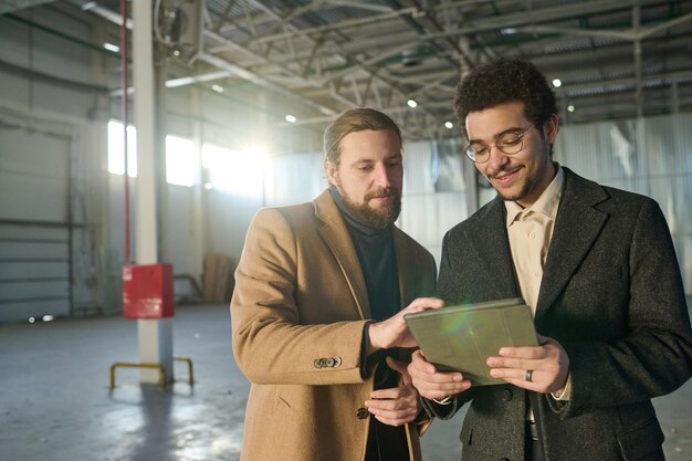 Foto due imprenditori interculturali in abiti formali discutono dello schizzo sullo schermo del tablet