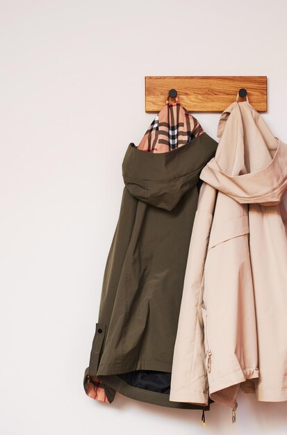 Фото Две куртки в бежевом и оливковом цвете висят на деревянной вешалке.