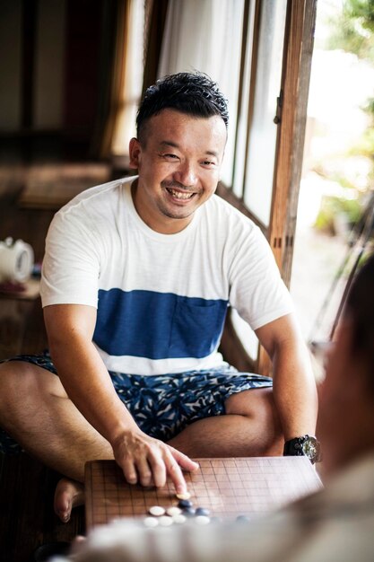 Two Japanese men and little boy sitting on floor on porch of traditional Japanese house playing Go