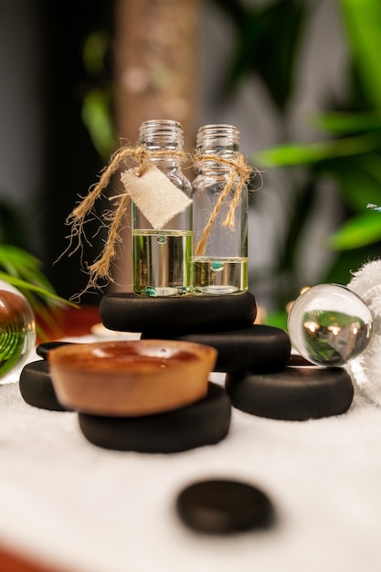 Two jars of aromatic oils standing on stones for therapy stone and located on a terry towel next to which are transparent spheres close-up