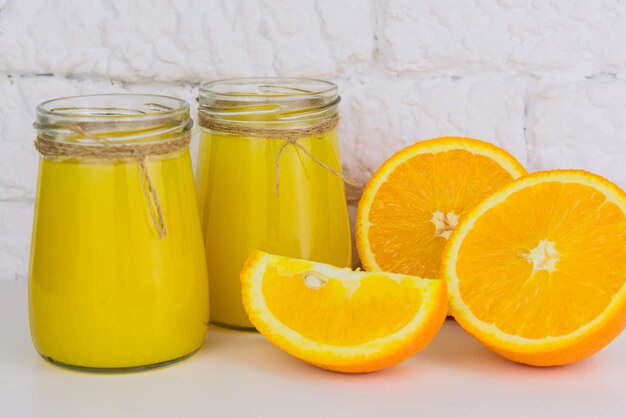 Two jars of fresh orange juice on a white background Closeup