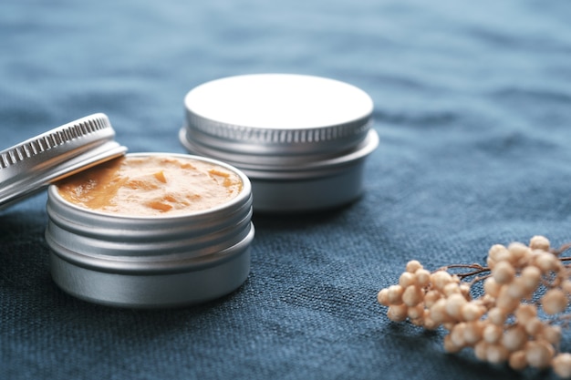 Photo two jars of natural cosmetic product on blue linen fabric