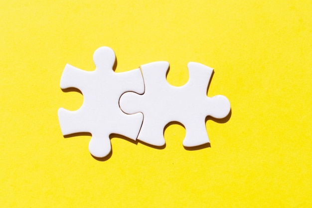 Two jigsaw puzzles pieces on illuminating yellow background