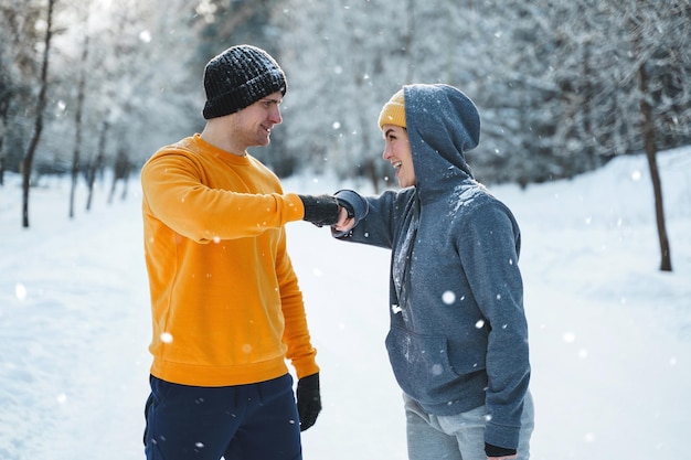 Two joggers greeting each other with a fist bump gesture during winter workout outside