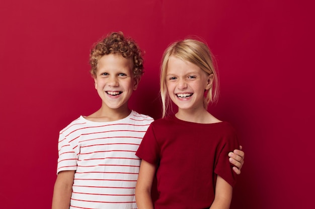 Two joyful children emotions stand side by side in everyday clothes isolated background