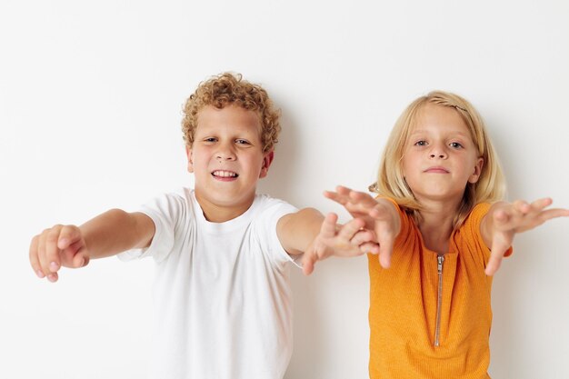 Two joyful children posing hand gesture smile casual wear light background