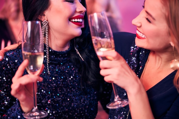 Две радостные женщины звенят бокалами с шампанским