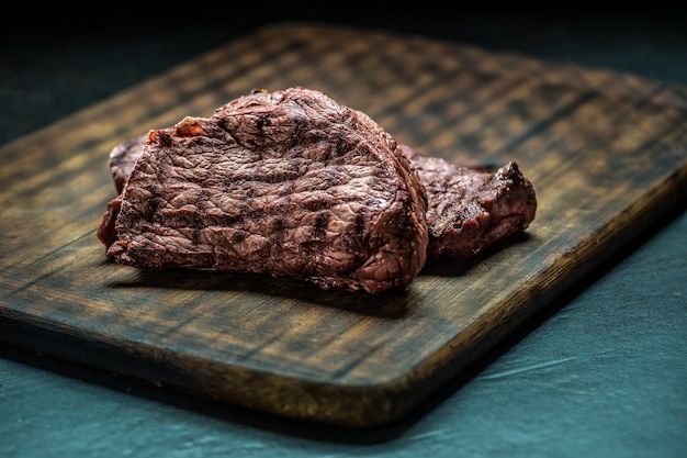 Two juicy beef rump steaks on butcher board.