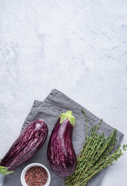 Two juicy eggplants with  thyme  and salt lie on a gray napkin on a blue concrete table village