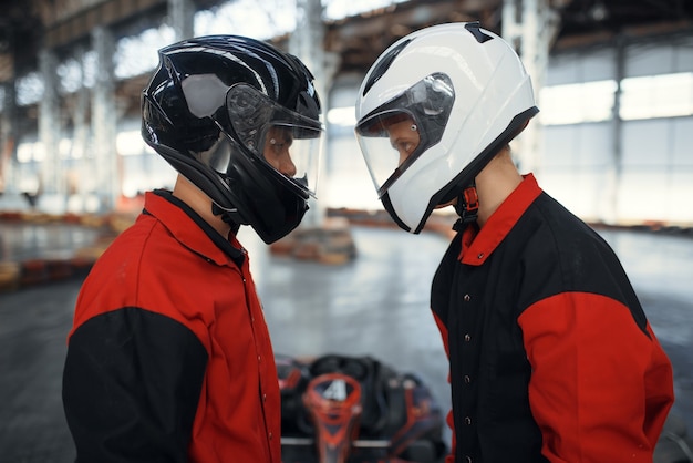 Photo two kart racers in helmets standing face to face
