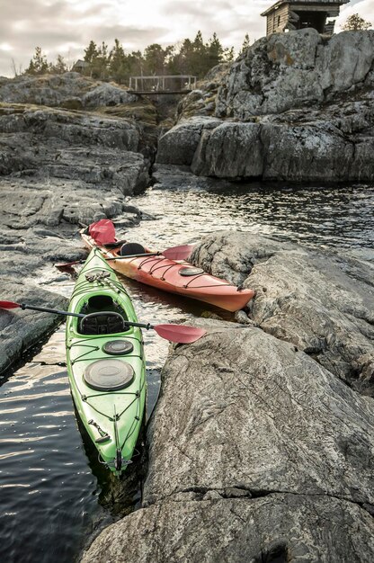 Two kayaks are moored on the rocky shore in the background you can see old wooden bridge and hut