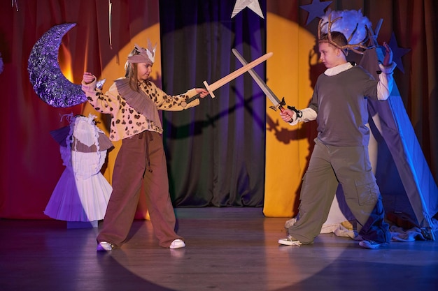 two kids acting out knights battle on stage of inclusive childrens theater