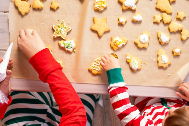 two kids boy and girl in pajamas cooking festive gingerbread in kitchen. top view