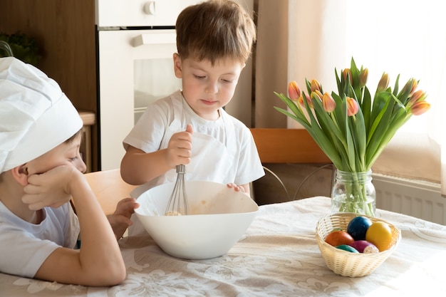 自宅のキッチンで料理をしている2人の子供の白人の男の子