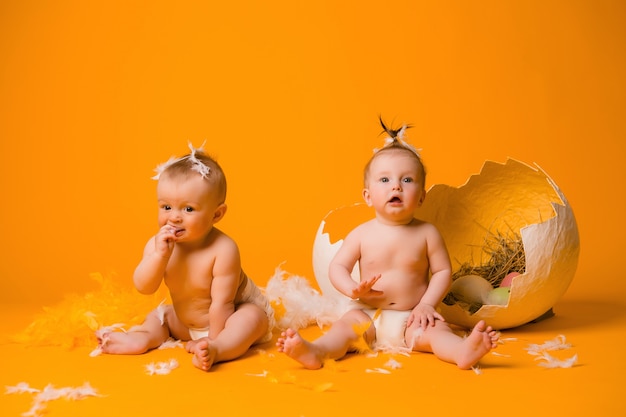 двое детей в курином костюме с яйцами на желтом, пасха
