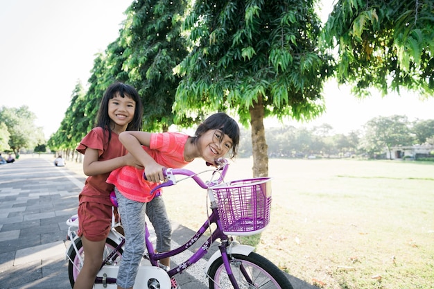 Two kids enjoy ride bike in the park togethe