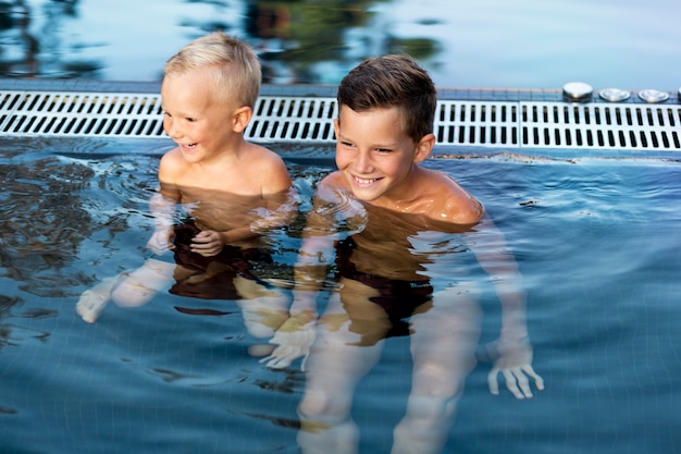 写真 スイミングプールで一日を楽しんでいる2人の子供