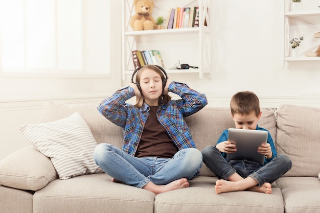 Two kids listening music on couch at home