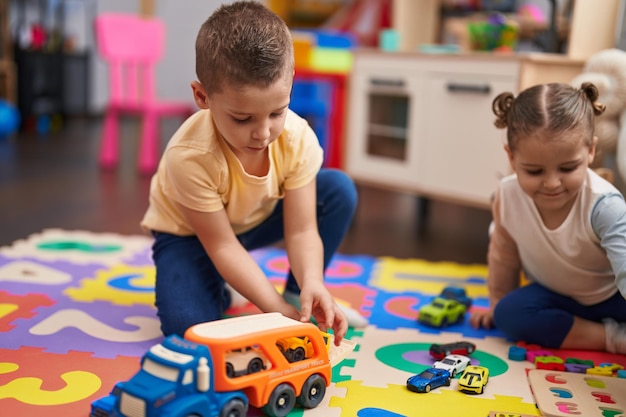 幼稚園で床に座って車のおもちゃと数学のゲームで遊ぶ 2 人の子供