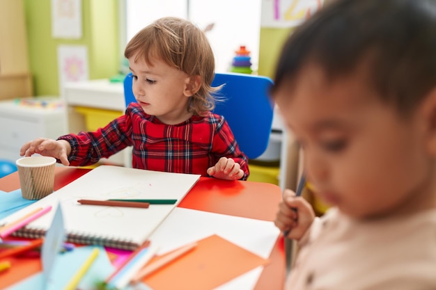 Foto due bambini in età prescolare studenti seduti sul tavolo disegno su carta all'asilo