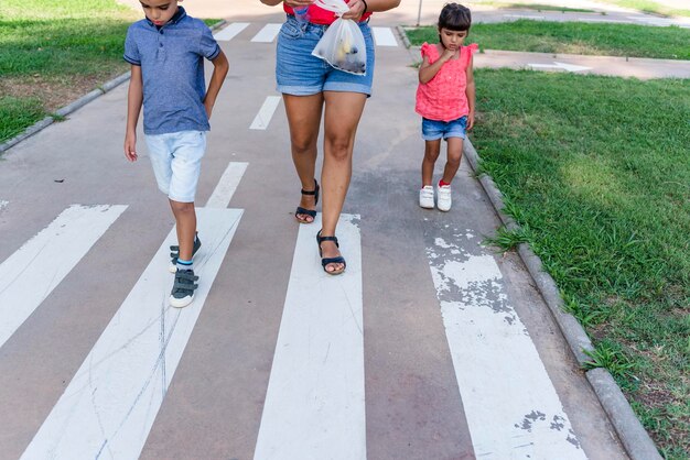 Photo two kids walking with their mother outdoors in a pathway in a park