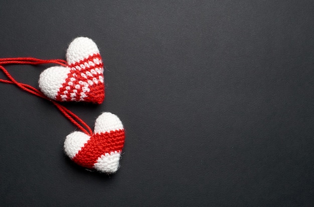 Two knitted handmade hearts on black paper