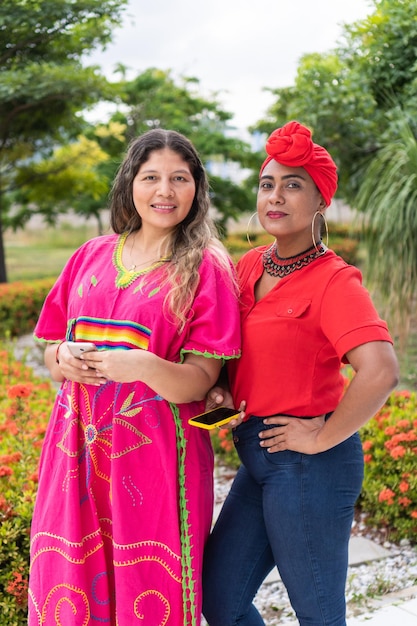 Two Latinas standing in the park looking at the camera